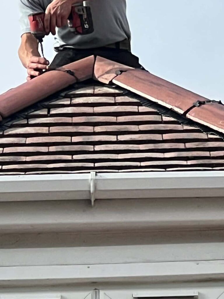 This is a photo of one of the operatives of Nettleham Roofing Repairs installing new ridge tiles